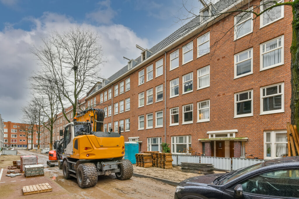 Renovatieproject van een woongebouw met bouwmachines en materialen op de werklocatie.
